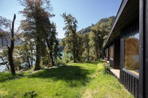 a house with a large window and a grass yard at Lodge Tagua Tagua, Puelo Patagonia in Puelo