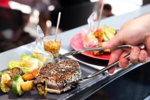 a person holding a plate of food on a tray at Le Pinarello in Sainte-Lucie de Porto-Vecchio