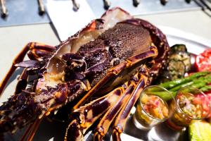 a lobster on a plate with vegetables on a table at Le Pinarello in Sainte-Lucie de Porto-Vecchio