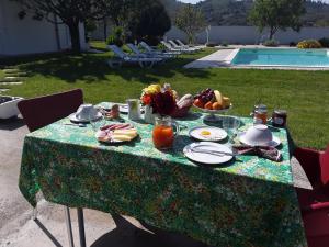 een tafel met eten erop naast een zwembad bij Quinta Camargue in Cela Velha