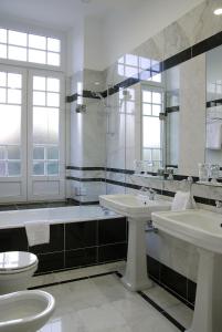 a bathroom with two sinks and a shower and a toilet at Curia Palace Hotel & Spa in Curia