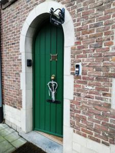 a green door in a brick building with a skeleton on it at Guesthouse La maison de Fille in Diest
