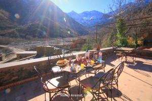 a table and chairs on a balcony with a view of a mountain at Hotel Aremd - Aroumd Imlil route du Toubkal in Imlil