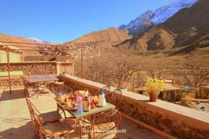 a table and chairs on a balcony with mountains at Hotel Aremd - Aroumd Imlil route du Toubkal in Imlil