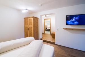 ein Wohnzimmer mit einem weißen Sofa und einem Flachbild-TV in der Unterkunft Gasthof Herrnhaus in Brixlegg