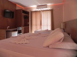 a bedroom with two beds with white sheets and a window at Planeta Hotel in Colinas Do Sul