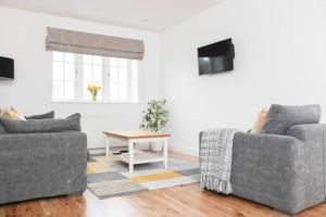 a living room with two couches and a table at Raynolds Cottage Blidworth in Blidworth