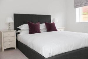 1 dormitorio con 1 cama blanca grande con almohadas moradas en Raynolds Cottage Blidworth, en Blidworth