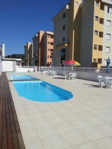 basen z krzesłami i parasolem na budynku w obiekcie Apartamento Sun Way Ubatuba- com piscina, churrasqueira e play ground w mieście Ubatuba