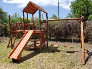 a wooden playground with a slide and a swing set at Cabaña El Refugio in Open Door