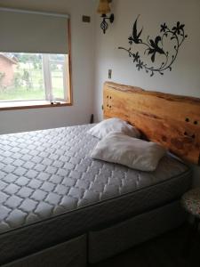 a bedroom with a bed with a wooden headboard and a window at Cabañas y Deptos Cuatro Estaciones in Frutillar