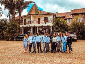 un grupo de personas parados frente a una casa en The Charity Hotel International, en Arusha