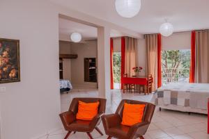 a bedroom with two chairs and a bed with orange pillows at Pousada Beira Rio in Itumbiara
