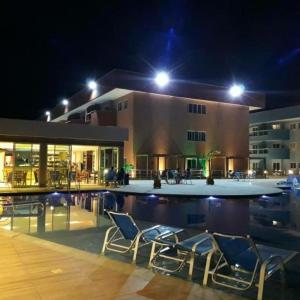 una piscina con sillas y un edificio por la noche en apart-hotel Golden Lake, en Arraial do Cabo