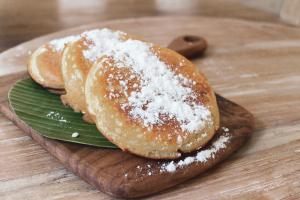 two donuts on a wooden cutting board with powdered sugar at ISLA INDAH RETREAT boutique hotel in Nusa Lembongan