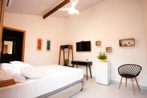 a white bedroom with a bed and a desk at EcoVilla Las Mareas in Maresias