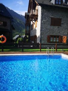 a large blue swimming pool in front of a building at Residencial Valle de Benasque in Benasque