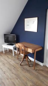 a living room with a wooden table and a tv at Maison d’hôtes KERGIQUEL in Paimpol