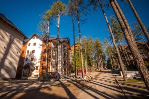 a car parked in front of a building with trees at Apartman Tajena in Zlatibor