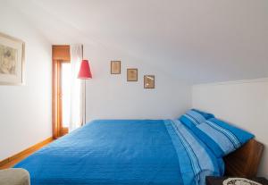 Un dormitorio con una cama azul y una ventana en La mansarda delle meraviglie B&B Superior, en Trieste