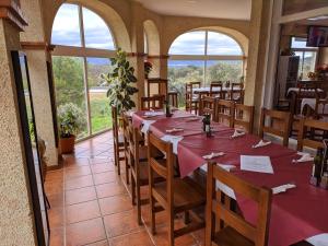 a dining room with tables and chairs and windows at Hostal La Dehesa in Villanueva del Rey