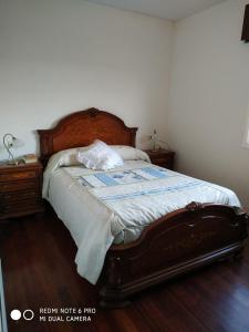 a bedroom with a large bed with a wooden headboard at Secondary home in Lobios