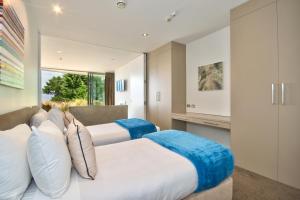 two beds in a room with a window at Lakes Edge Apartment in Queenstown