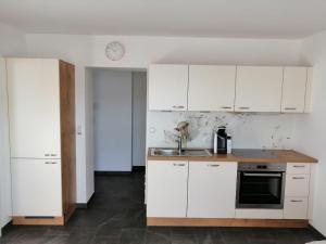 an empty kitchen with white cabinets and a sink at Apartment Peotta in Volders