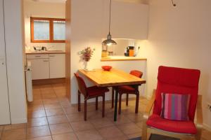 eine Küche und ein Esszimmer mit einem Holztisch und roten Stühlen in der Unterkunft Paradix holiday apartment - gîte 4, 2 pers in Nissan-lez-Enserune