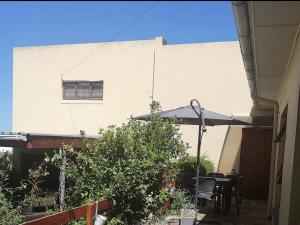 a patio with a table and chairs and an umbrella at Rooftops in Bredasdorp