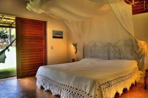 una camera da letto con un letto bianco con baldacchino di Casa Cacau a São Miguel do Gostoso