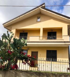 une maison jaune avec une clôture devant elle dans l'établissement La Rinella, à Caria