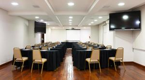una sala de conferencias con mesas, sillas y una pantalla en B&B HOTEL Uberlândia en Uberlândia