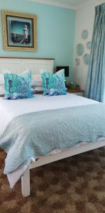 a bedroom with a large bed with blue pillows at Rooftops in Bredasdorp