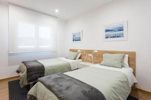 Duas camas num quarto com paredes brancas em APARTAMENTO LUMINOSO EN CANGAS em Cangas