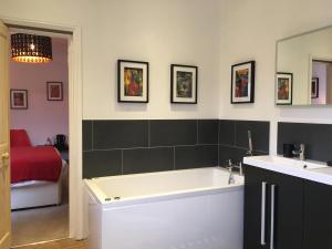 a bathroom with a tub and two sinks and a bed at Holway House in Sheringham
