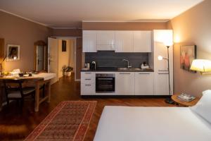 uma cozinha com armários brancos e uma mesa num quarto em S. Trinità 18, Suites & Rooms em Trento