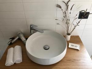 La salle de bains est pourvue d'un lavabo blanc sur une table en bois. dans l'établissement La Rinella, à Caria