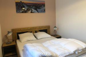 APPARTEMENT 8 personnes LODGES A505 في La Plagne Tarentaise: سرير عليه وسادتين في غرفة النوم