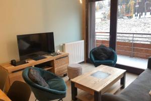 APPARTEMENT 8 personnes LODGES A505 في La Plagne Tarentaise: غرفة معيشة مع تلفزيون وكراسي وطاولة