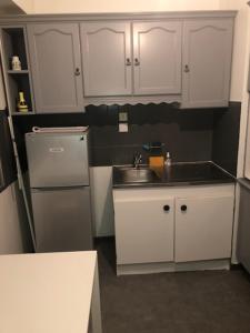 cocina con armarios blancos, fregadero y nevera en APPART PORT DU CANAL, en Dijon