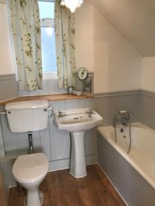 a bathroom with a toilet and a sink and a bath tub at Inglenook Cottage in Grange Over Sands