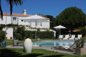 a pool with an umbrella and chairs and a house at Blanc Marine in Noirmoutier-en-l'lle