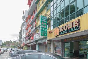 uma rua com carros estacionados em frente aos edifícios em Hotel Rose Crest Hill em Tanah Rata