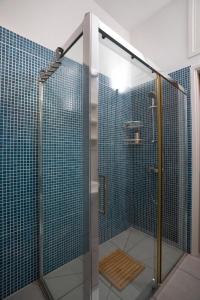 y baño con ducha de azulejos azules. en Athenaeum Beachside Apt by TrulyCyprus en Limassol