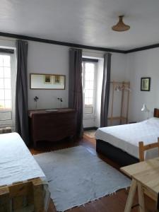 a bedroom with two beds and a table and two windows at Casa da Lomba do Cavaleiro in Povoação