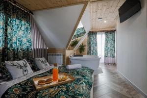 łazienka z wanną i łóżko z tacą z jedzeniem w obiekcie GÓRALSKA VILLA APARTAMENTY Z JACUZZI & HOME SPA & Zakopane w Poroninie