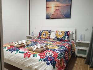uma cama com um edredão colorido e almofadas em BRISAS DEL MAR APARTMENT, ONE STEP FROM THE SEA. em Playa del Burrero