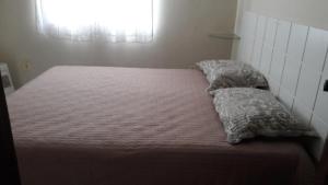 Bett in einem kleinen Zimmer mit Fenster in der Unterkunft Casa Temporada Rio das Ostras in Rio das Ostras