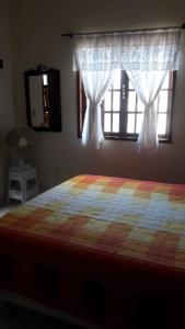 ein Schlafzimmer mit einem Bett und einem Fenster mit Vorhängen in der Unterkunft Casa Temporada Rio das Ostras in Rio das Ostras